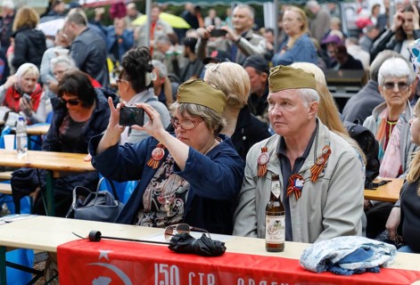 A man and a woman wear caps from Russian uniforms on the 74th anniversary of the victory of Russia