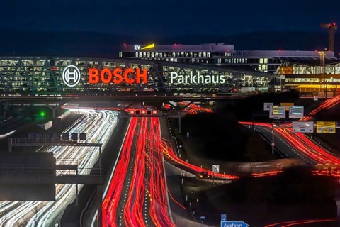 A8 motorway at Stuttgart Airport with Bosch multi-storey car park in the evening, cars create light
