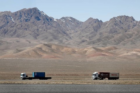 Truck on a motorway in the central desert of Iran, snow-capped mountains can be seen in the