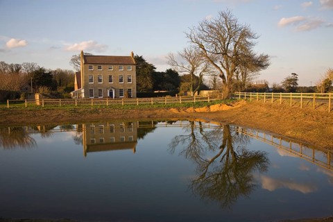 High House Farm farmhouse reflected in water of newly dug pond, Bawdsey, Suffolk, England, United