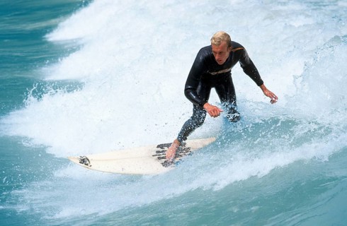 Young man surfing on river Isar during floods, Wittelsbacherbruecke, Munich, Bavaria, Germany,