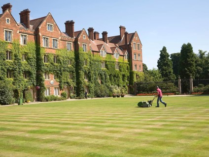 Man mowing grass lawn in courtyard of Selwyn College, University of Cambridge, England, United