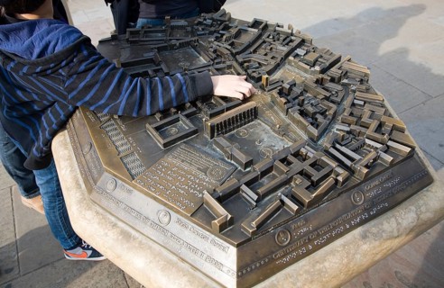 Child pointing at location on three dimensional model of the city centre, Cambridge, England,
