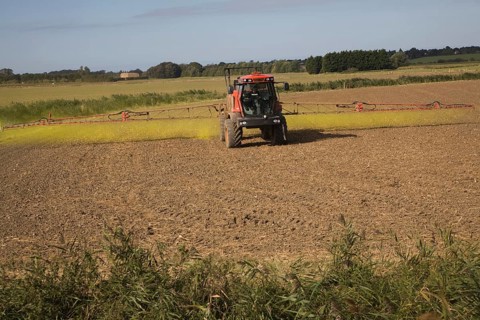 Farm machinery spraying Glyphosate herbicide on an arable field near Hollesley, Suffolk, England,