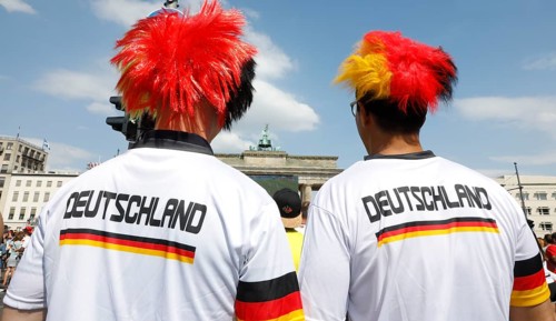 Football fans wear wigs with the colours of the German flag for the World Cup opening match between