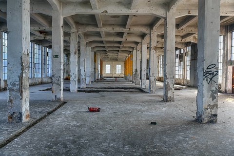 Empty dilapidated factory building, pillars, peeling paint, light entering through broken window
