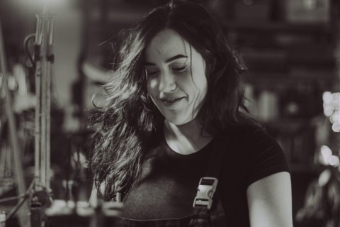 Hispanic latino long haired brunette sexy woman mechanic examining a car part in a well-equipped