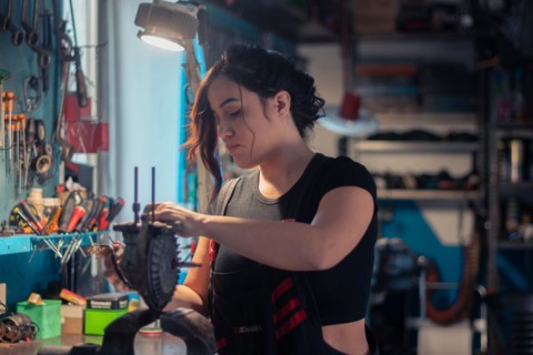 A craftswoman is carefully engaged in repair work, surrounded by tools in her occupation, a