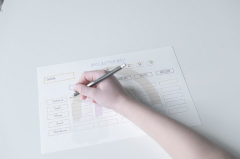 Diabetes log, daily log of food and insulin administration, food log, hand of a child holding a pen
