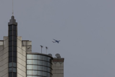 Airbus A319-100 aircraft of British airways in flight over a city skyscraper building, London,