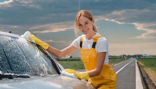 AI generated, A blonde woman washes a car by hand, silver sports car