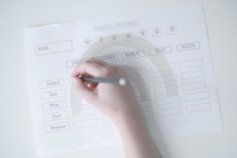 Diabetes log, daily log of food and insulin administration, food log, hand of a child holding a pen