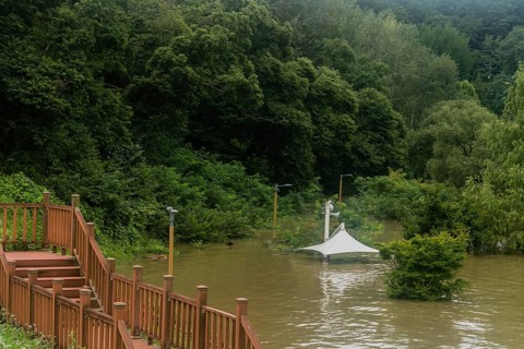 White awning over flooded river where picnic table has been submerged under water from monsoon