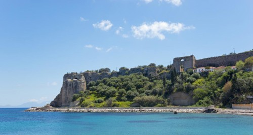 View of a sunny coastal landscape with blue sea, historic ruins and lush vegetation, Byzantine