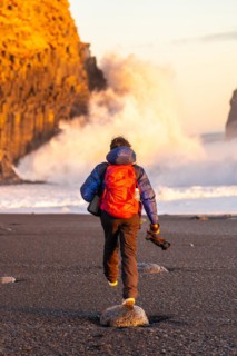 Adventurous photographer woman from behind in winter in Iceland visiting the Reynisfjara Black Sand