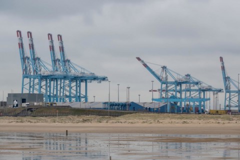 Reflection of harbour cranes and containers on the water under a cloudy sky, Zeebrugge, Flanders,