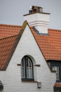 The gable of a house with tiled roof and skylight against a cloudy sky, DeHaan, Flanders, Belgium,