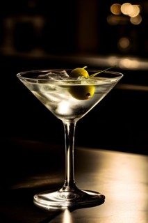 Gin martini with an olive resting on a polished bar top ambient lighting, AI generated