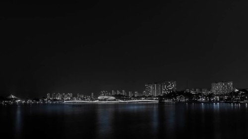 A serene black and white night shot of city skyline reflections on water, in South Korea