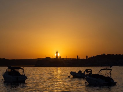 Boats anchoring in a bay, sunset, silhouette of the church towers of Rab, town of Rab, island of