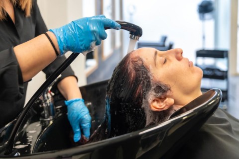 Hairstylist washing the hair of a woman in a sink in a beauty salon