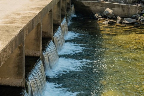 Water flowing smoothly over a concrete dam spillway, in South Korea