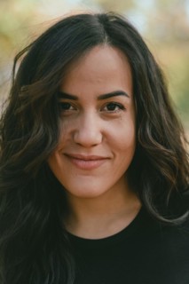 Serene outdoor portrait of a Cheerful hispanic young woman with a slight smile, appearing