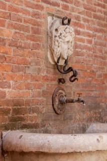 Detail of the Mencia Fountain in the historic centre of Asciano, Crete Senesi, Tuscany, Italy,