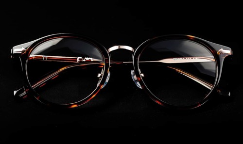 Round eyeglasses with an elegant gold bridge and thin frame against a dark background AI generated