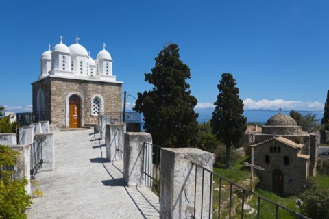 Church with classical architecture, surrounded by trees and blue sky, on the right Temple of Apollo