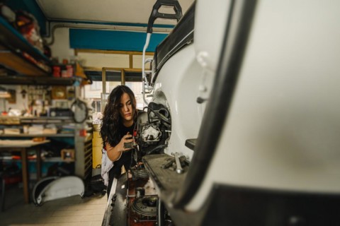 Female mechanic engaging in hands-on motorbike maintenance at a workshop station, latino woman in
