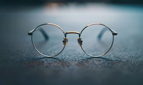 Round minimalist eyeglasses with a thin metal frame on a reflective surface AI generated