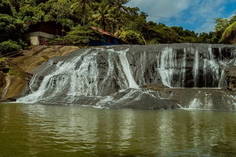Landscape of a waterfall taken with ND filter with trees and blue sky in the background and water