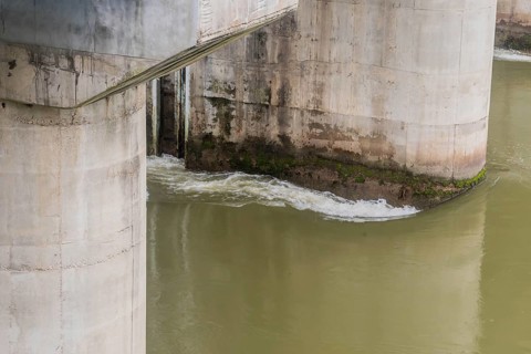 Algae and moss on a concrete bridge structure show signs of water flow and erosion, in South Korea