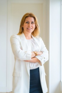 Vertical portrait of a proud female estate agent standing with arms crossed in the office