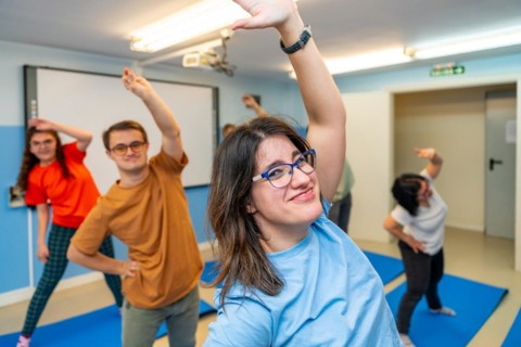 Happy people with special needs exercising in a gym smiling and looking at camera standing