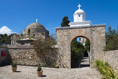 Traditional chapel behind an old wall under a clear blue sky on a sunny day, Stone church with