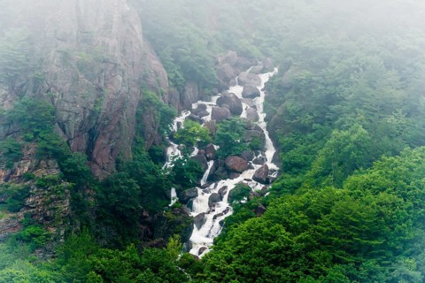 A stunning waterfall with misty waters plunging through rocky cliffs covered in greenery, in South