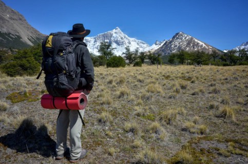 Hiker with a heavy rucksack in front of the snow-covered summit of Monte San Lorenzo, Perito Moreno