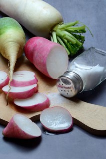 Various radishes on a wooden board, cut up and sliced