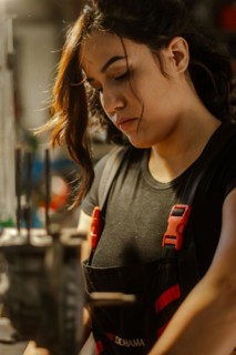 Woman mechanic in deep focus and contemplation while making mechanical adjustments in dimly lit