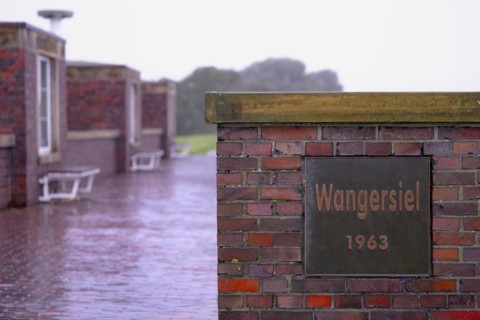 Wangersiel 193, metal sign at the harbour of Horumersiel on a red brick wall, in the background
