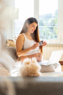 Vertical photo of a breauty adult pregnant woman showing baby ultrasound in video call using laptop