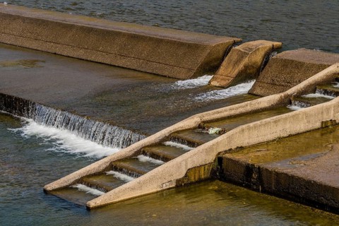 Concrete river dam with water overflowing on a sunny day, in South Korea