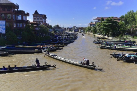 People on boats on a river with city silhouette in the background, Pindaya, Inle Lake, Myanmar,