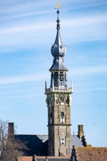 Old tower with a clock and spire rising above lower buildings, Middelburg, Zeeland, Netherlands