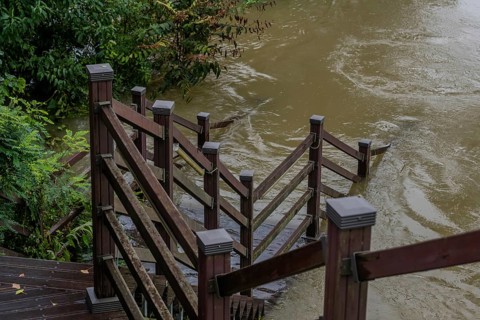Wooden staircase leading to boardwalk submerged in river after torrential monsoon rains in Daejeon