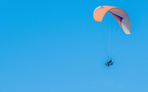 Paraglider in flight against a serene blue sky, exemplifying extreme sports, in South Korea