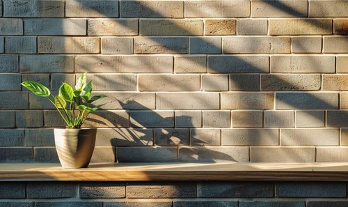 Sunlight filters through blinds, casting shadow patterns over a plant on a shelf against a brick