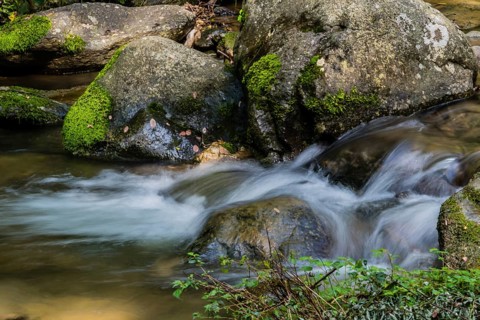 Small water fall cascading down rocks in the middle of a small mountain stream in Guam